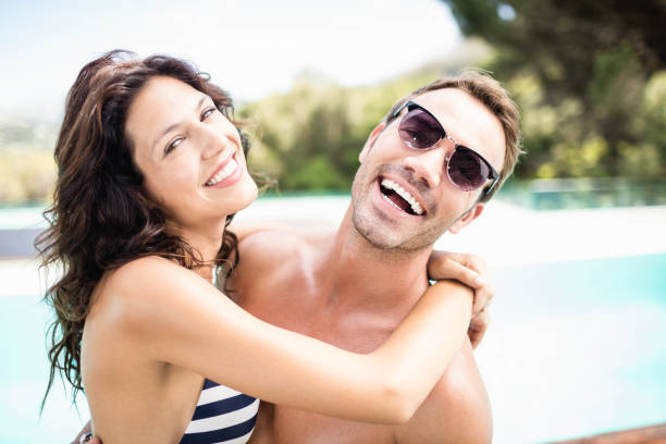 istock Young couple cuddling each other near pool 674647452