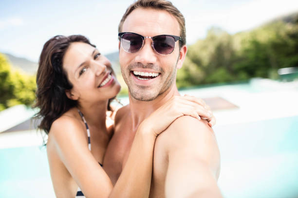 istock Young couple smiling near pool 674647518
