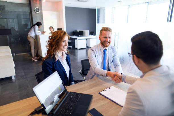 Couple talking to loan officer and shaking hands stock photo