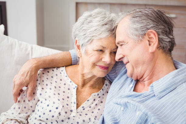 vue grand angle romantique couple âgé assis sur le canapé - couple affectionate relaxation high angle view photos et images de collection