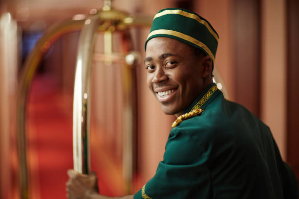 Luggage service Smiley young bellboy pushing cart with luggage bellhop stock pictures, royalty-free photos & images