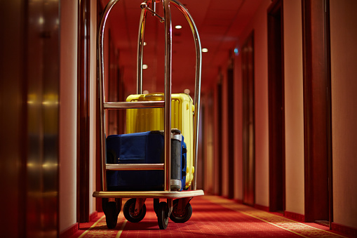 Cart of porter with suitcases in aisle of hotel
