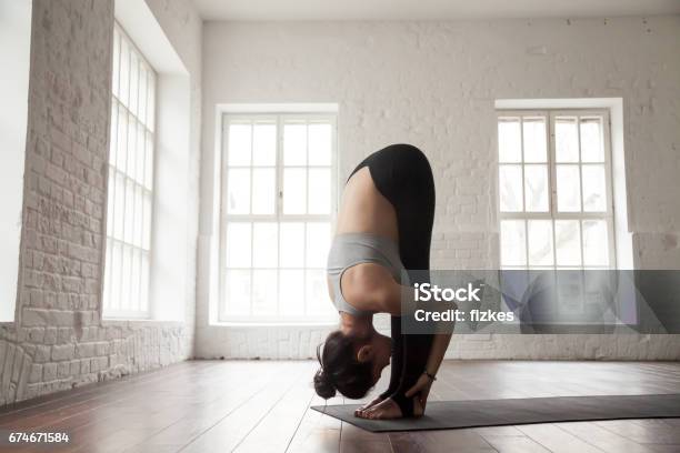 Young Woman In Head To Knees Pose White Loft Studio Stock Photo - Download Image Now