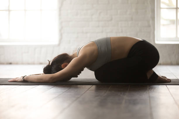 giovane donna sportiva in posa balasana, backgroun studio loft bianco - bikram yoga pilates beautiful foto e immagini stock