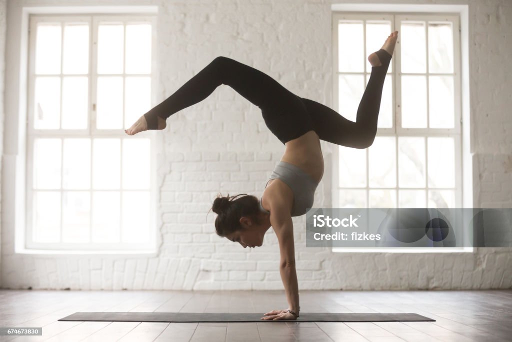 Young attractive woman in Adho Mukha Vrksasana pose, white studi Silhouette of young cool attractive yogi woman practicing yoga concept, standing in Adho Mukha Vrksasana exercise, Downward facing Tree pose, working out, wearing sportswear bra and pants, full length Handstand Stock Photo