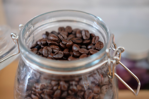 Lot of roasted coffee beans in glass jar, close up