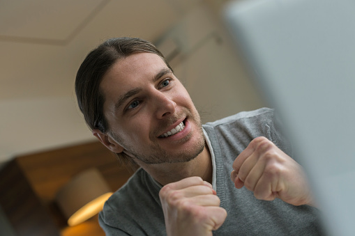 Ecstatic young businessman celebrating in front of her laptop