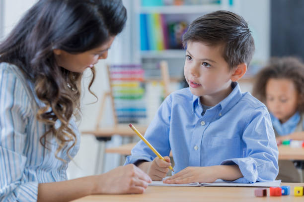 young schoolboy works with his teacher at school - mathematics elementary student child student imagens e fotografias de stock