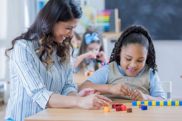 istock Teacher works with young girl in math class 674688230