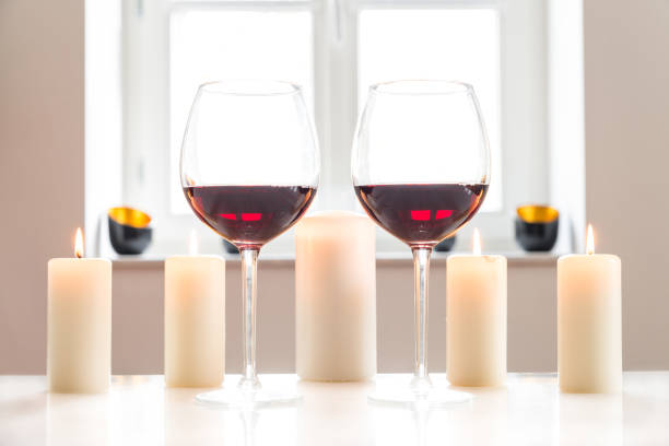 istock Two glasses with red wine on white table with white background and window 674701660