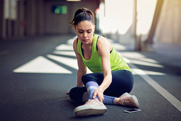 Injured runner sitting on the ground with broken mobile phone Injured runner sitting on the ground with broken mobile phone joint and muscle pain  stock pictures, royalty-free photos & images