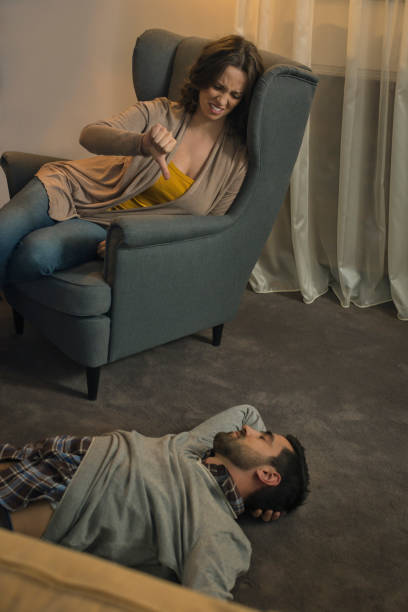 istock Women showing thumb down on man who sleeps on floor 674711896