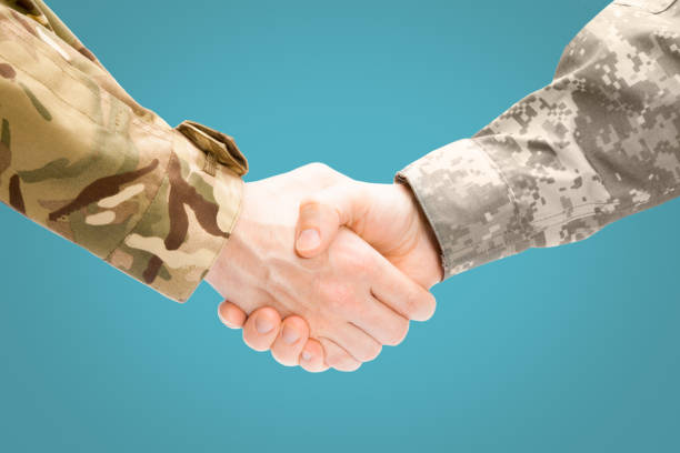 istock Two military men shaking hands on white background - close up studio shot 674730980