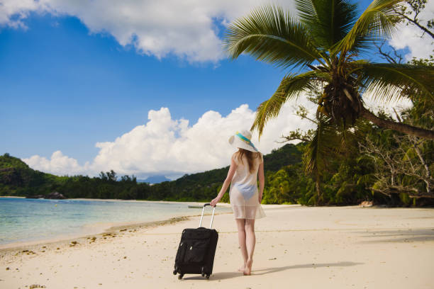 istock Girl with a suitcase on the beach 674759896