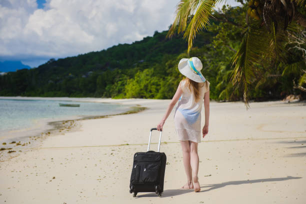 istock Woman with a suitcase on a tropical beach. 674759898
