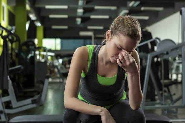 Woman having headache after working out in a health club stock photo