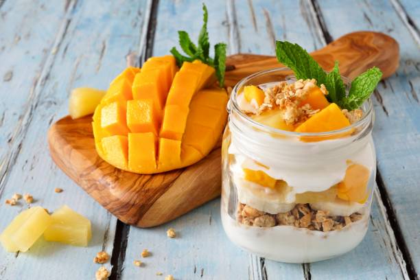istock Mango, pineapple parfait in a mason jar on rustic blue wood 674781584