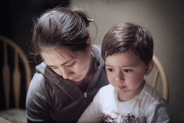 Dramatic portrait of a young Asian woman and her young son mourning the death of a father Dramatic portrait of a young Asian woman and her mixed race asian caucasian young son mourning news of the death of a father woman comforting depressed friend stock pictures, royalty-free photos & images