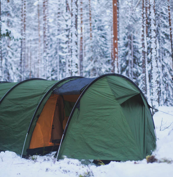 istock A process of camping in winter forest, setting a tent covered in snow, making a bonfire campfire and cooking food with portable gas cooker and fire, snowy landscape 674799732