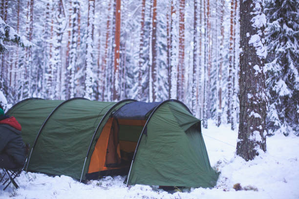 istock A process of camping in winter forest, setting a tent covered in snow, making a bonfire campfire and cooking food with portable gas cooker and fire, snowy landscape 674799748