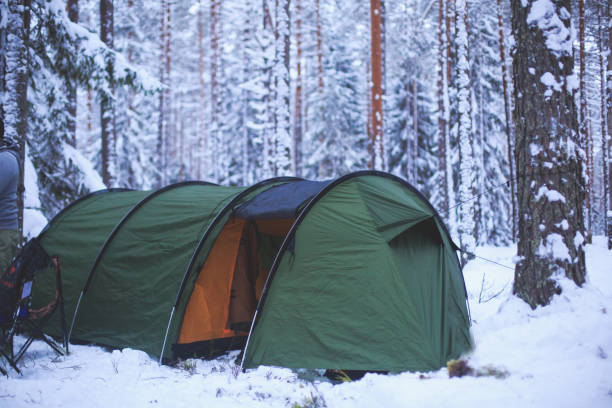 istock A process of camping in winter forest, setting a tent covered in snow, making a bonfire campfire and cooking food with portable gas cooker and fire, snowy landscape 674799756