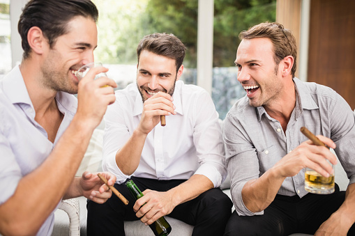 Group of men smoking and drinking while discussing