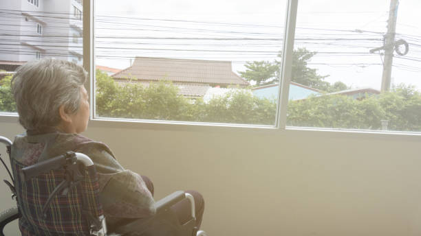 istock lonely senior looking through window in building - age, loneliness and people concept 674807192