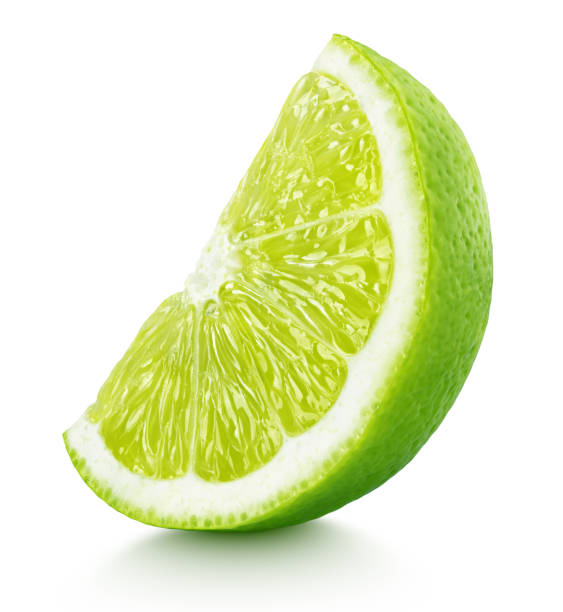 wedge of green lime citrus fruit isolated on white Ripe slice of green lime citrus fruit stand isolated on white background with clipping path lime photos stock pictures, royalty-free photos & images