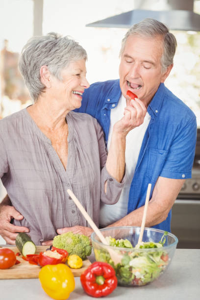 istock Happy senior woman feeding husband while standing at counter 674818400