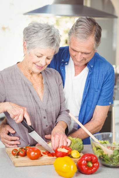 istock Senior woman cutting while man embracing in kitchen 674818466