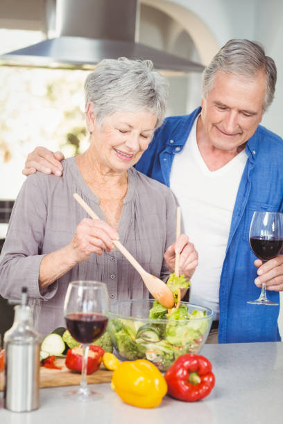 istock Senior woman preparing salad while man standing at counter 674818570