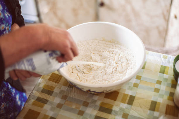 Grandmother pouring milk into pancake batter. Preparing batter for pancakes