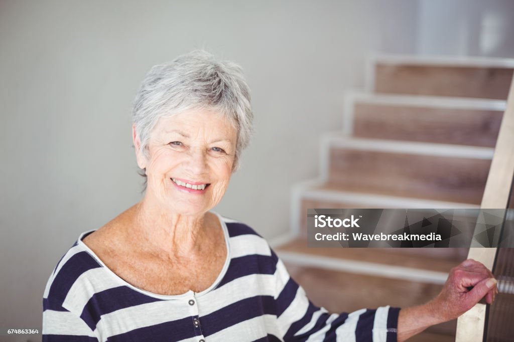 Portrait of happy senior woman against staircase Portrait of happy senior woman against staircase at home Staircase Stock Photo