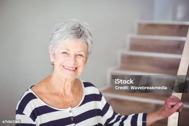 Portrait Of Happy Senior Woman Against Staircase Stock Photo - Download Image Now - Staircase, Senior Adult, Steps