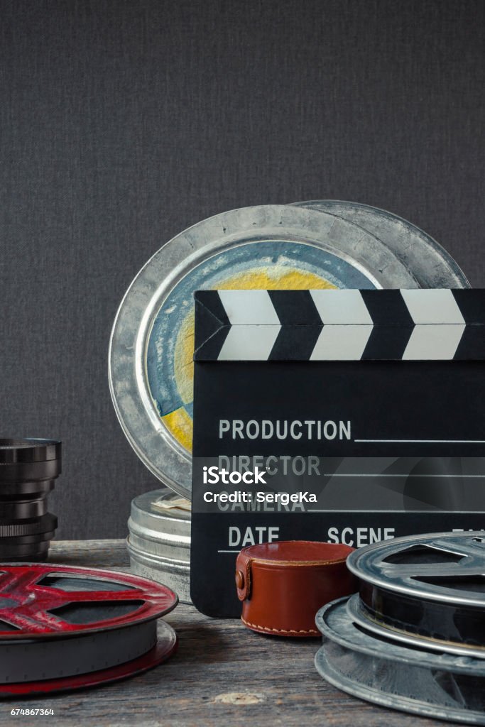 Clapperboard,  a box of film and lens Clapperboard, tin boxes with film and lens stand on a wooden table. Film Reel Stock Photo