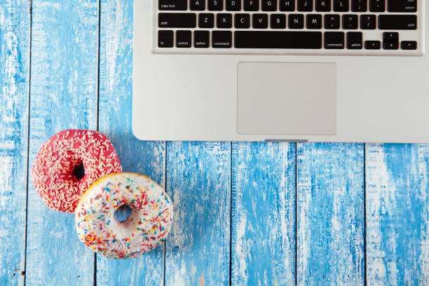 istock Top view of laptop with donuts on wooden table 674893718
