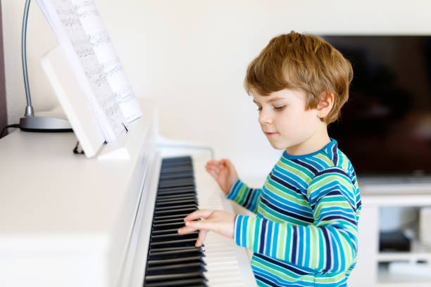 美しい小さな子供男の子リビング ルームや音楽学校でピアノを弾く - one little boy audio ストックフォトと画像
