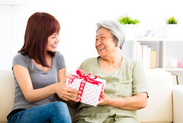 szczęśliwa młoda kobieta dająca prezent babci - gift mothers day birthday giving zdjęcia i obrazy z banku zdjęć