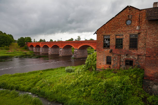Old brick bridge over Venta river in Kuldiga, Latvia. Summer time.
