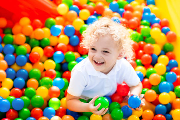 child playing in ball pit on indoor playground - ball pool imagens e fotografias de stock