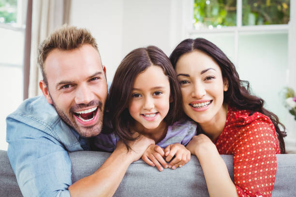 istock Happy parents with daughter on sofa at home 674923634