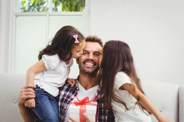 istock Father holding gift box and daughters kissing him 674924172