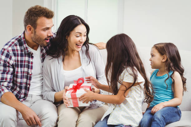 istock Daughters giving gift to surprised parents 674927414