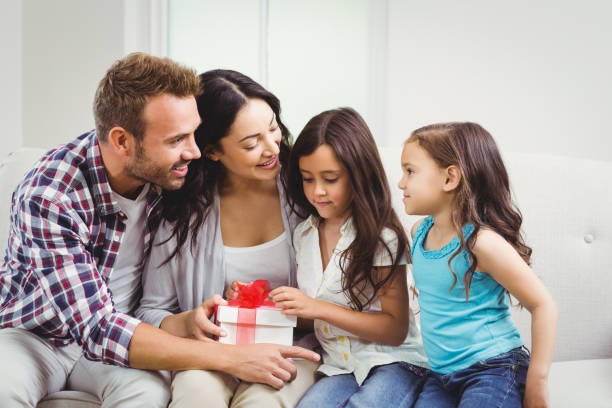 istock Happy parents with daughters holding gift 674927482