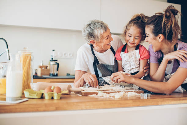 lovely little girl cooking with mom and granny - grandmother cooking baking family imagens e fotografias de stock