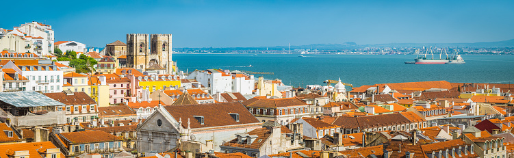 Panoramic vista over the terracotta rooftops of Baixa to the iconic square towers of the Se Cathedral and the blue waters of the Tagus in the heart of Lisbon, Portugal’s vibrant capital city.