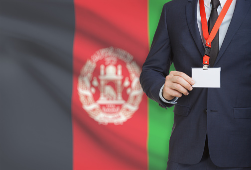 Businessman holding name card badge on a lanyard with a flag on background - Afghanistan