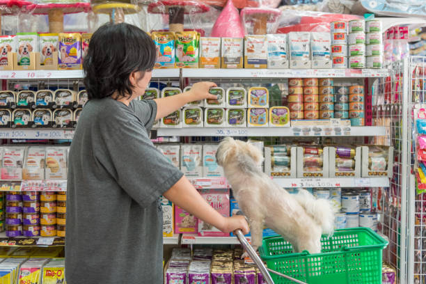 Women and her dog shop a pet food (Dog, Cat and other) on pet goods shelf in pet shop. stock photo