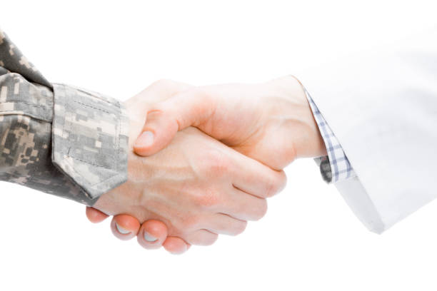 istock Doctor and military man shaking hands on white background - close up studio shot 674953290