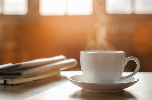 coffee cup with newspaper on the table, coffee shop background, warm tone